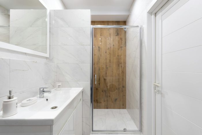 Bright modern bathroom with white tiles and a glass shower door