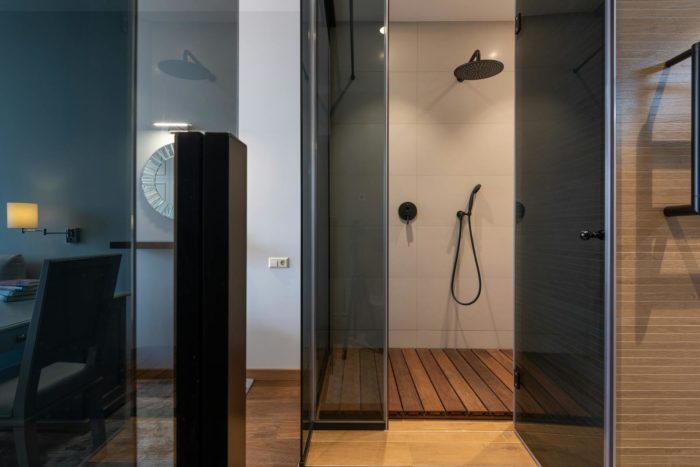 Glass-walled shower with wooden flooring in a contemporary bathroom